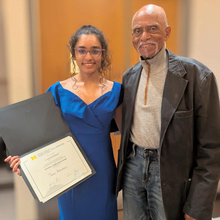 Woman with award smiling next to man